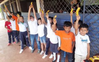 students hold up fruit