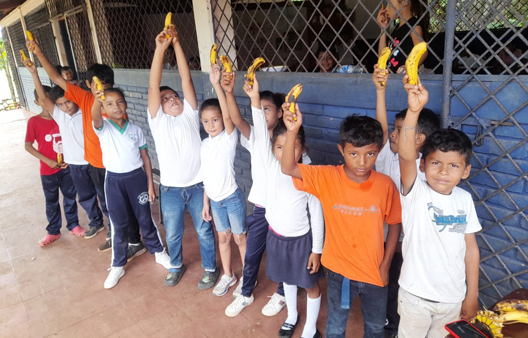 students hold up fruit