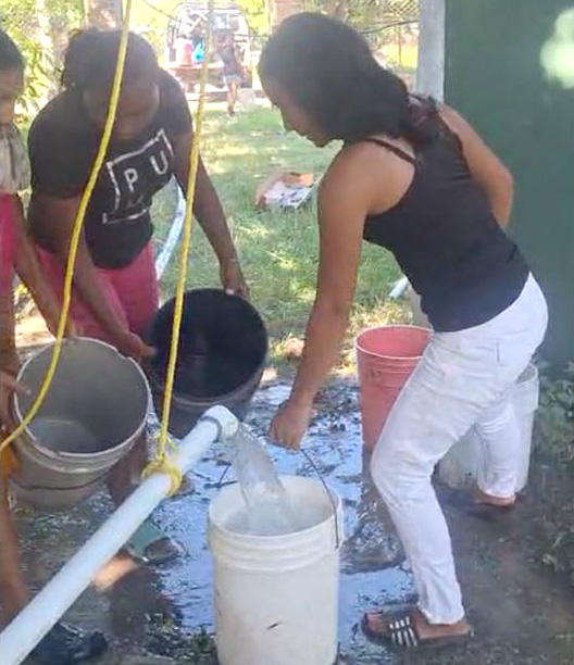 Women filling buckets from new water well.