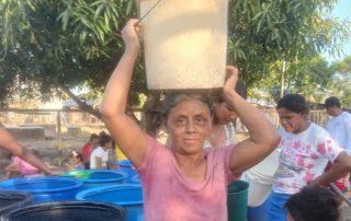 Woman carrying water bucket on head.