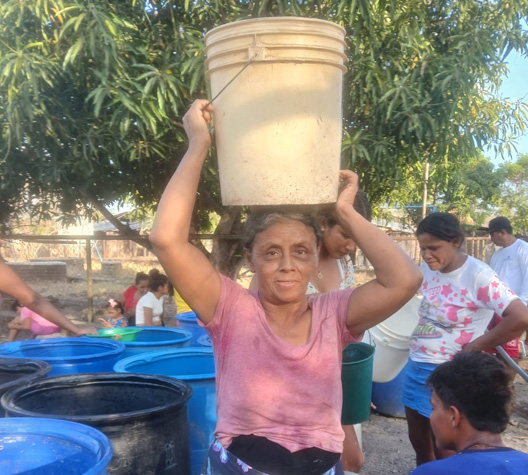 Woman carrying water bucket on head.